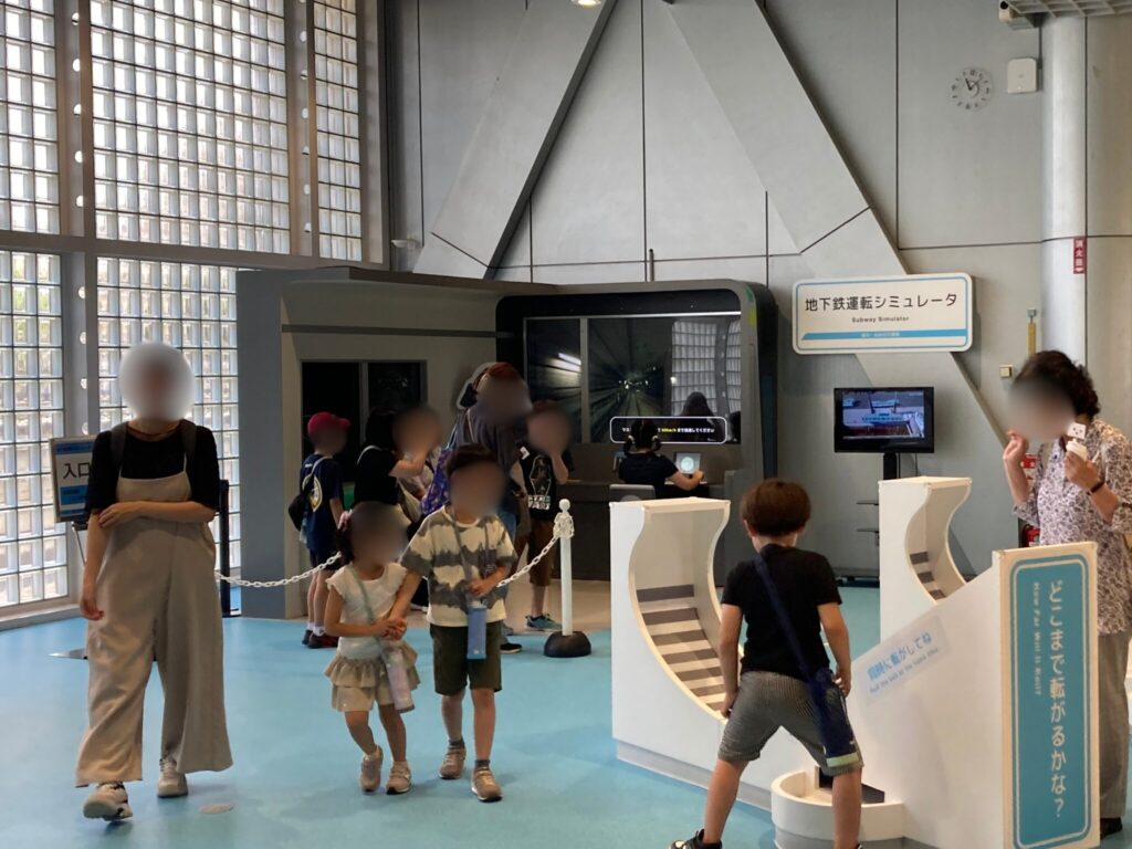 仙台市科学館の地下鉄シミュレーターに小学生が並んでいる様子